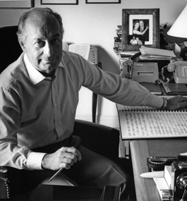 In an undated photo, Lazarof sits with one arm leaning on a desk, his glasses in his hand, which rests on a wire-bound book of music manuscripts.